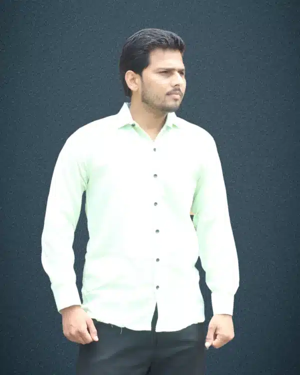 A man wearing a full-sleeve mint green shirt with a subtle vertical texture and black pants, looking directly at the camera.