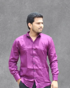 A man wearing a vibrant purple textured full-sleeve shirt, standing against a gray background.