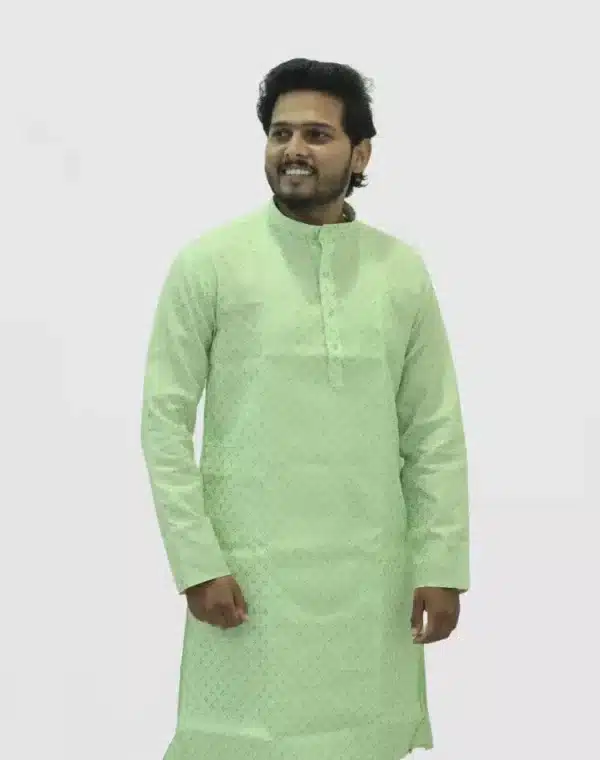 : A man smiling and wearing a light mint green full-sleeve kurta with a gold dotted or geometric print.