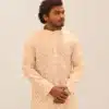 A male model wearing a full-sleeve, ivory or off-white kurta with a gold patterned foil print, suitable for Diwali and festive occasions.