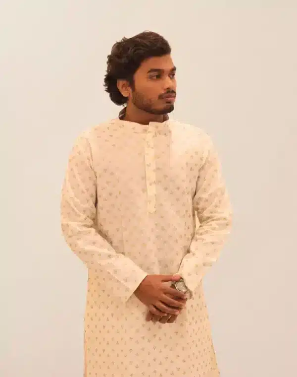 A male model wearing a full-sleeve, ivory or off-white kurta with a gold patterned foil print, suitable for Diwali and festive occasions.